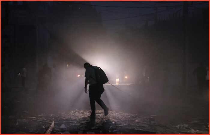 Foto dal New York Times a corredo dell'articolo del militare israeliano. Un uomo si fa strada lungo una strada disseminata di detriti di notte dopo gli attacchi aerei israeliani sulla città di Gaza sabato.
