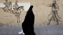Donna con velo passa di fronte ad un murale