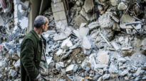 Un uomo osserva un edificio distrutto dal terremoto