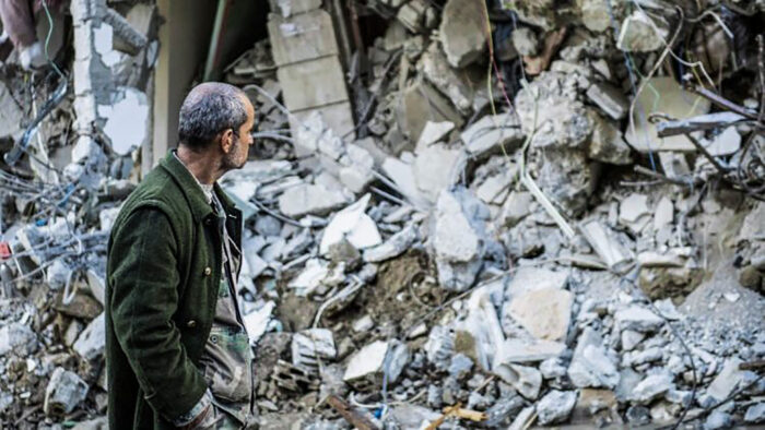 Un uomo osserva un edificio distrutto dal terremoto. Il Congresso Usa vota per ripristinare tutte le sanzioni alla Siria